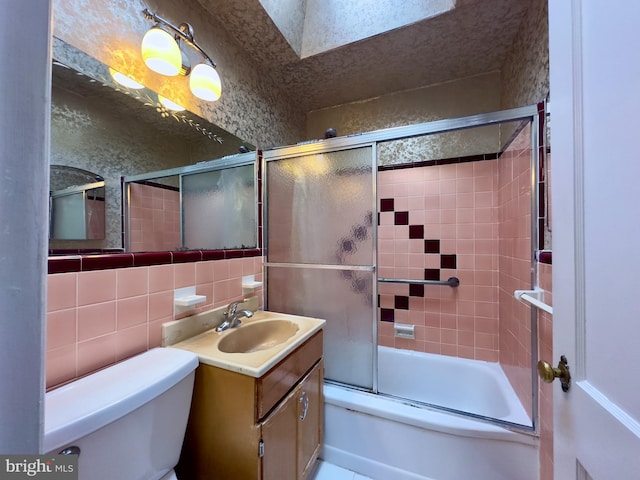 bathroom featuring tasteful backsplash, tile walls, toilet, combined bath / shower with glass door, and vanity