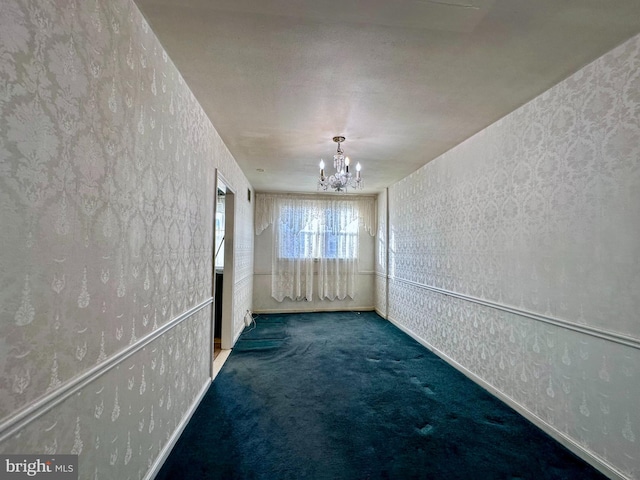 carpeted spare room featuring wallpapered walls and a notable chandelier