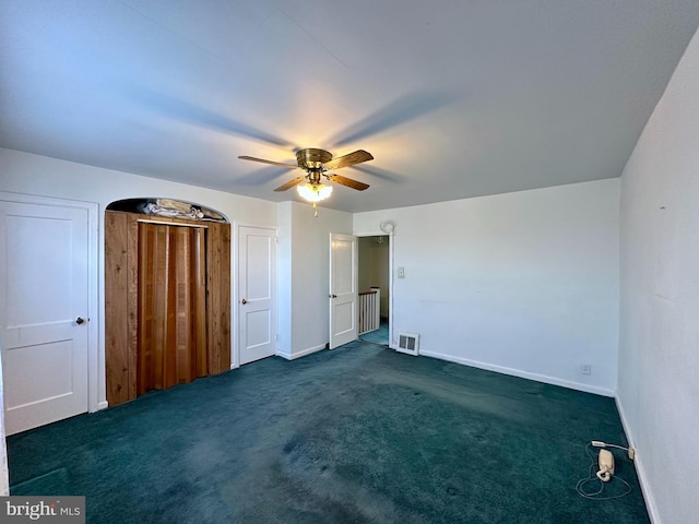 unfurnished bedroom with dark colored carpet, visible vents, baseboards, and ceiling fan