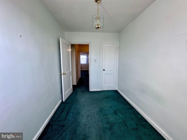 unfurnished room featuring dark carpet and baseboards