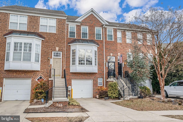 multi unit property with a garage, concrete driveway, and brick siding