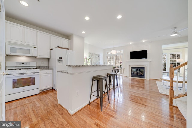 kitchen featuring light stone counters, white appliances, white cabinetry, open floor plan, and light wood-type flooring