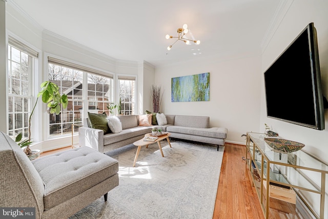 living area with ornamental molding, baseboards, an inviting chandelier, and hardwood / wood-style flooring