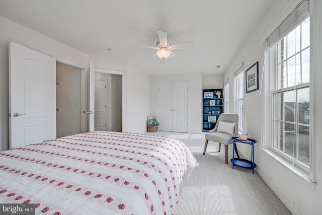 bedroom featuring a ceiling fan, a closet, and light colored carpet