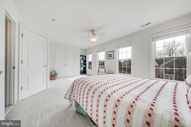 bedroom with a ceiling fan, a closet, visible vents, and light colored carpet