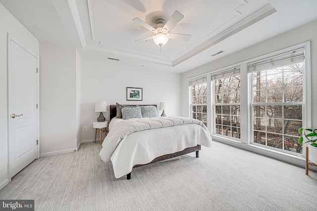 bedroom with light carpet, a tray ceiling, and ornamental molding