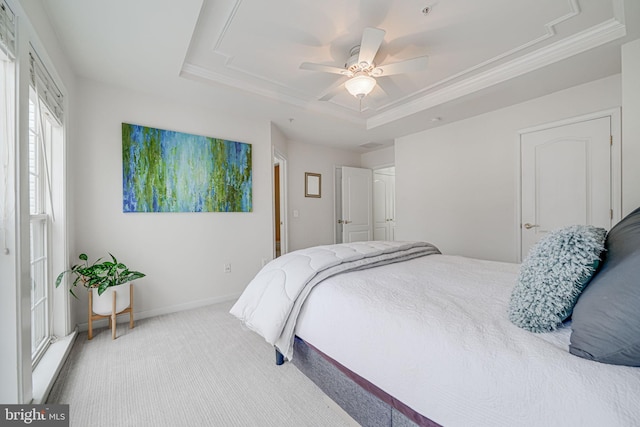 bedroom with ceiling fan, carpet floors, baseboards, ornamental molding, and a tray ceiling