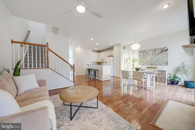 living room featuring light wood-style flooring, stairway, baseboards, and recessed lighting