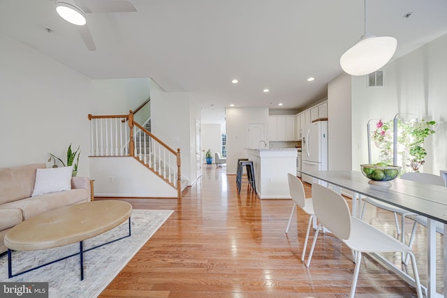 dining space with light wood finished floors, recessed lighting, visible vents, ceiling fan, and stairs