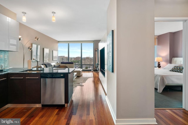 kitchen featuring dark countertops, open floor plan, a sink, a wall of windows, and dishwasher