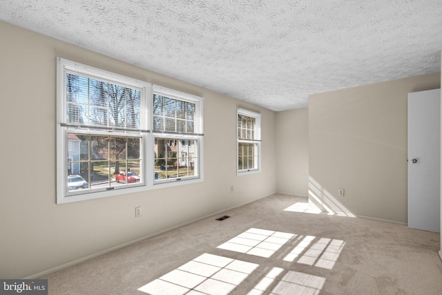 unfurnished room with a textured ceiling, light carpet, and baseboards