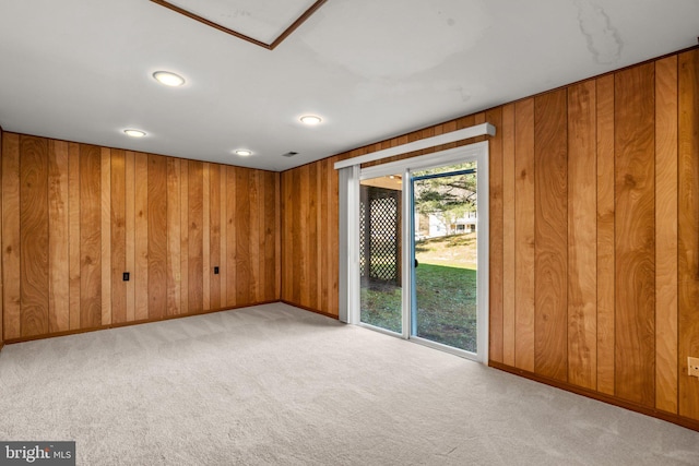 empty room with visible vents, wooden walls, baseboards, and light colored carpet