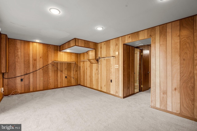 interior space with light carpet, wood walls, and baseboards