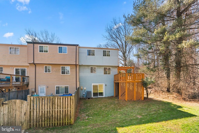 rear view of house with a lawn, fence, a wooden deck, and central air condition unit