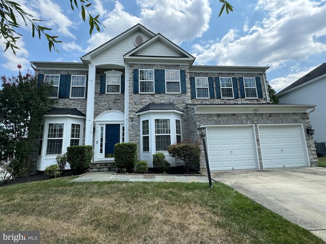 view of front of house with concrete driveway, stone siding, and a front yard