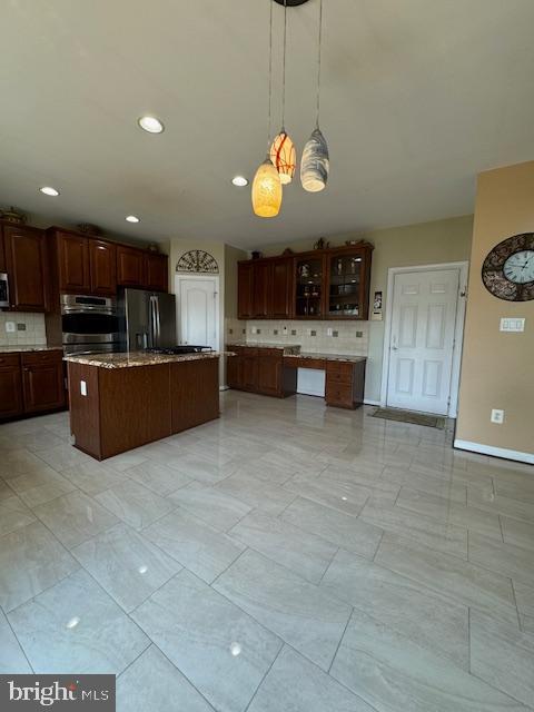 kitchen with decorative light fixtures, glass insert cabinets, tasteful backsplash, and freestanding refrigerator