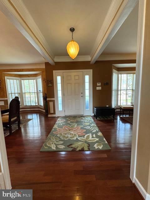 foyer entrance with beamed ceiling, crown molding, baseboards, and wood finished floors