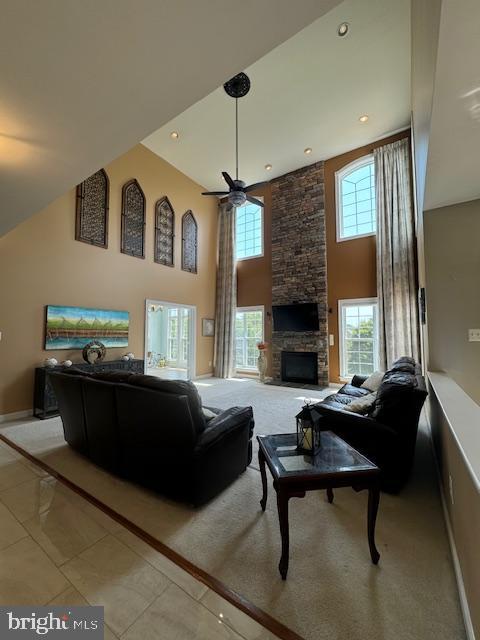 living room with baseboards, ceiling fan, recessed lighting, a fireplace, and a high ceiling