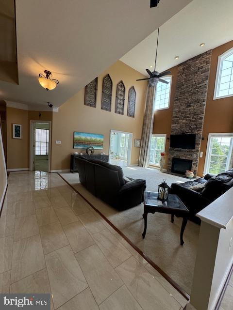 living room featuring a healthy amount of sunlight, a fireplace, a towering ceiling, and ceiling fan