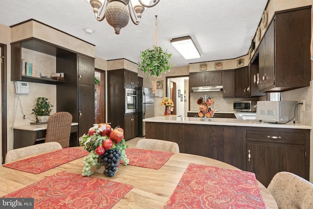 kitchen with stainless steel appliances, light countertops, decorative backsplash, dark brown cabinets, and a peninsula