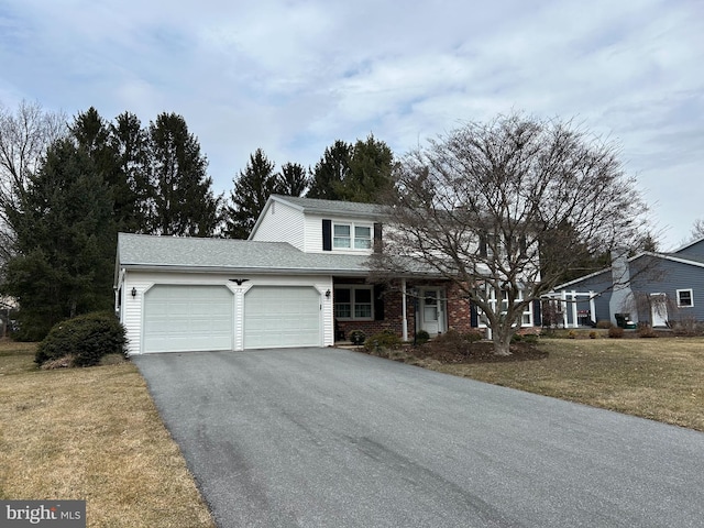 traditional-style home featuring a garage, a front yard, brick siding, and driveway