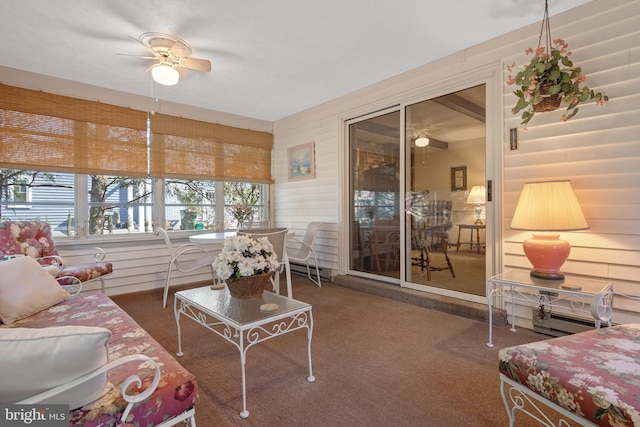 living area with carpet, wooden walls, and ceiling fan