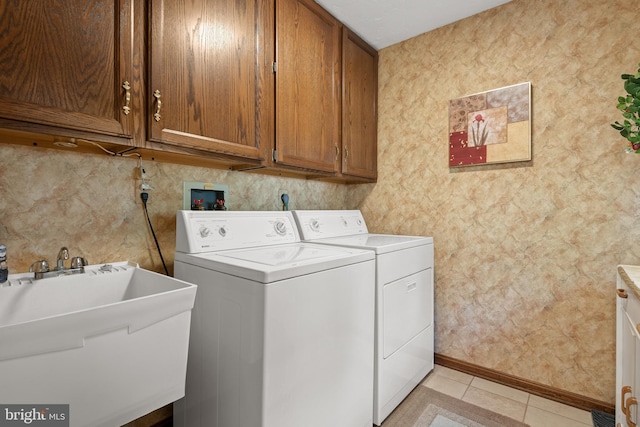 washroom with light tile patterned floors, a sink, baseboards, cabinet space, and washer and clothes dryer