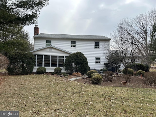 rear view of house featuring a sunroom, a yard, and a chimney