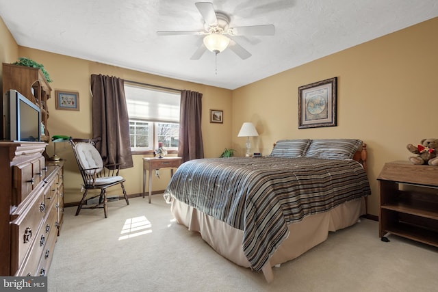 bedroom featuring a ceiling fan, light carpet, a textured ceiling, and baseboards