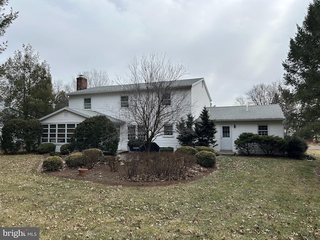 rear view of house with a chimney and a lawn