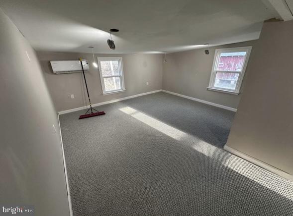 below grade area with carpet, baseboards, and a wall mounted air conditioner