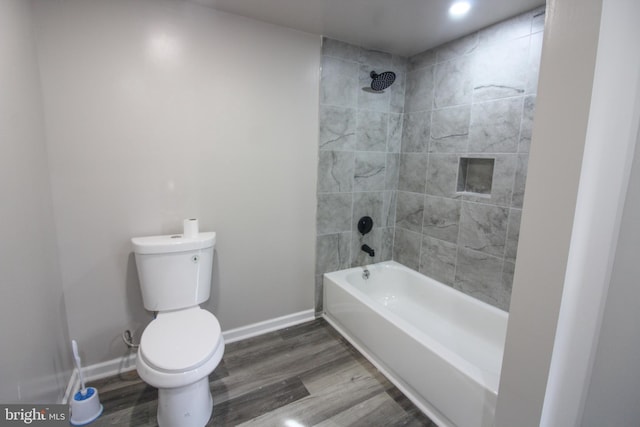 bathroom featuring washtub / shower combination, toilet, baseboards, and wood finished floors