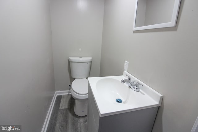 bathroom featuring baseboards, vanity, toilet, and wood finished floors