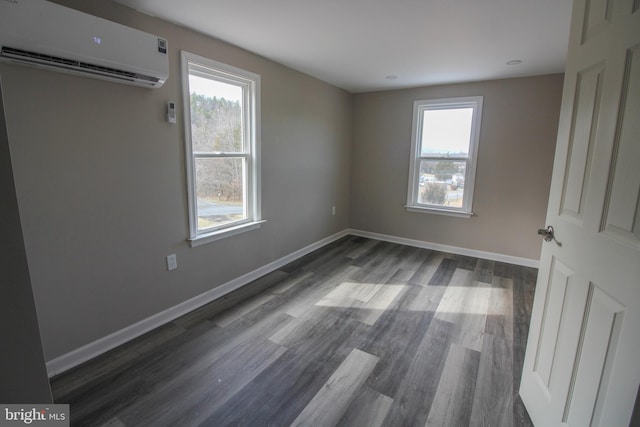 unfurnished bedroom featuring multiple windows, baseboards, dark wood-type flooring, and an AC wall unit