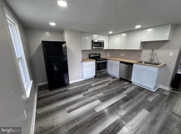 kitchen with stainless steel appliances, dark wood-style flooring, white cabinetry, and a sink