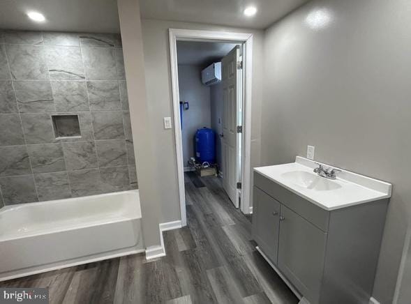 full bathroom featuring baseboards, wood finished floors, tub / shower combination, an AC wall unit, and vanity