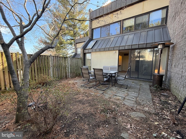 back of house with outdoor dining area, a patio area, a fenced backyard, and stucco siding