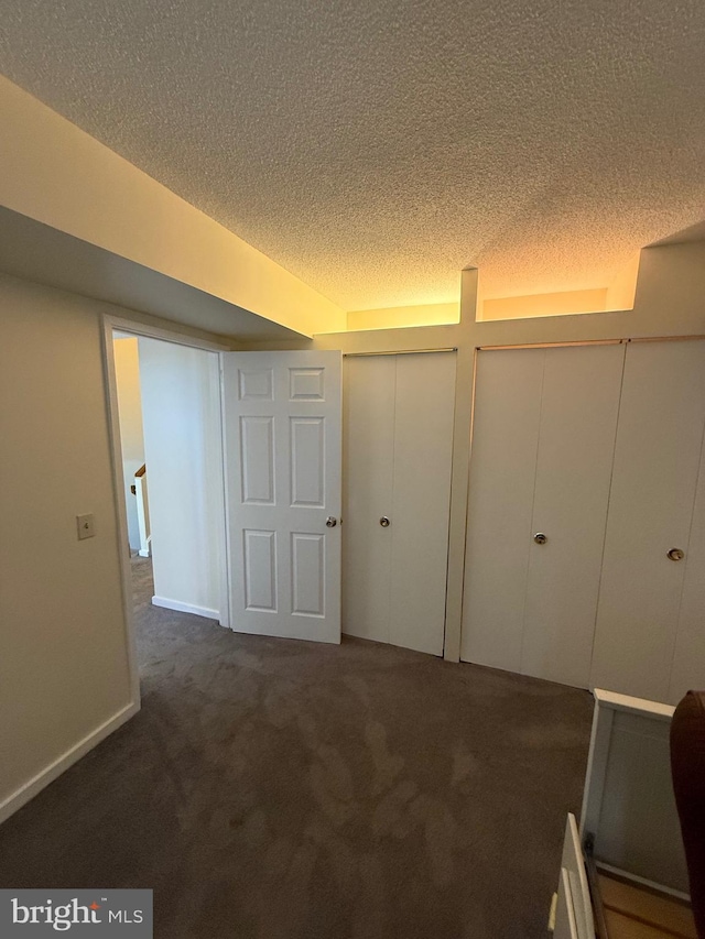 interior space with dark carpet and a textured ceiling