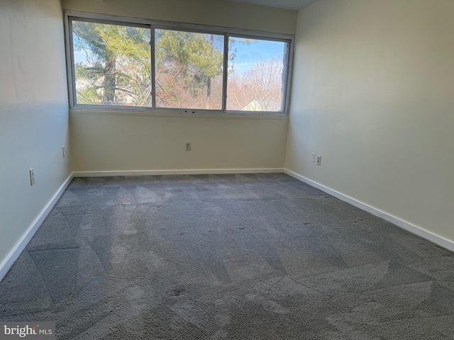 empty room with baseboards and dark carpet