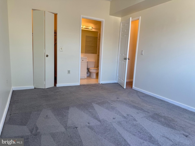 unfurnished bedroom with ensuite bath, baseboards, and carpet flooring