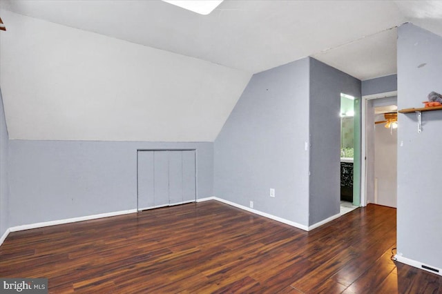 additional living space featuring dark wood-style floors, lofted ceiling, and baseboards