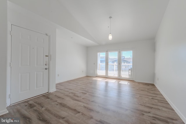 unfurnished room featuring lofted ceiling, light wood-style flooring, and baseboards