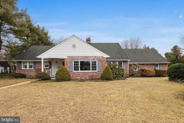 view of front of property with brick siding, a chimney, a front yard, and a shingled roof