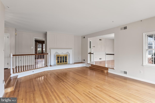 unfurnished living room featuring a glass covered fireplace, visible vents, and a healthy amount of sunlight