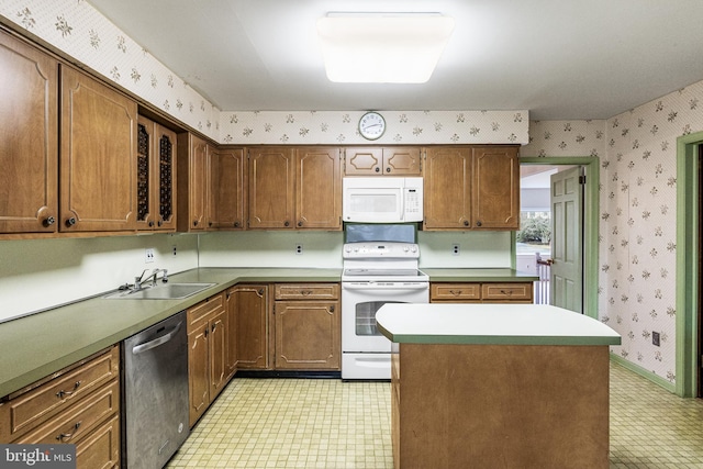 kitchen with wallpapered walls, white appliances, a kitchen island, light floors, and a sink