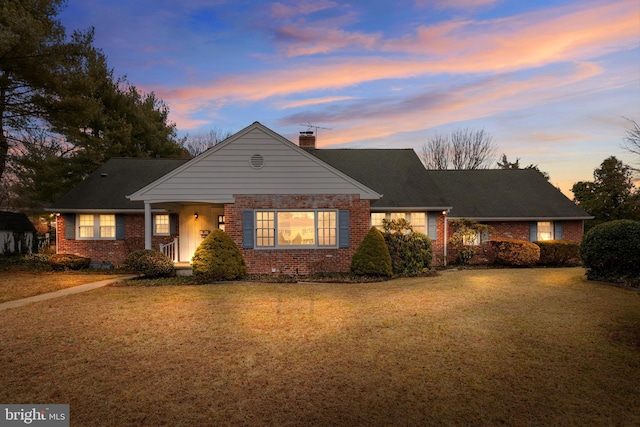 view of front of home with brick siding, a chimney, and a front lawn