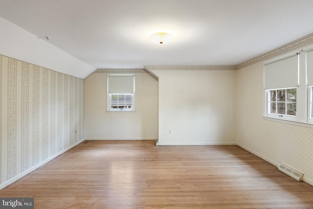 bonus room with plenty of natural light, light wood-type flooring, visible vents, and wallpapered walls