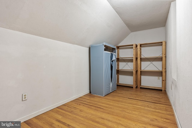 additional living space featuring lofted ceiling, baseboards, a textured ceiling, and light wood finished floors