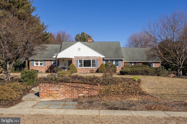 view of front of home featuring brick siding and a chimney