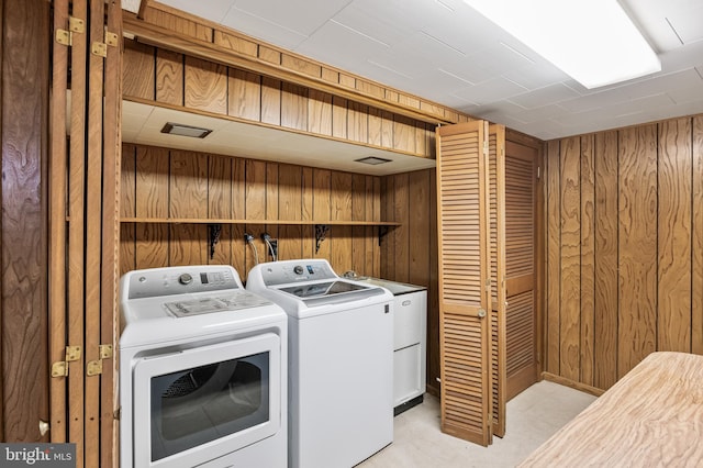 washroom with laundry area, washer and dryer, and wooden walls